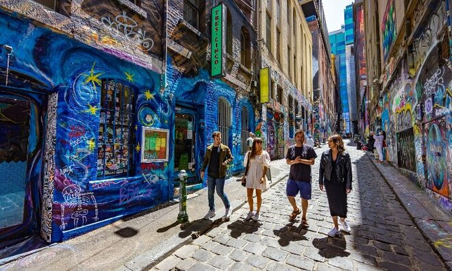 Four people walking down an alley covered in street art. 