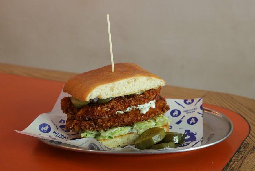 A fried chicken sandwich with pickles on the side.