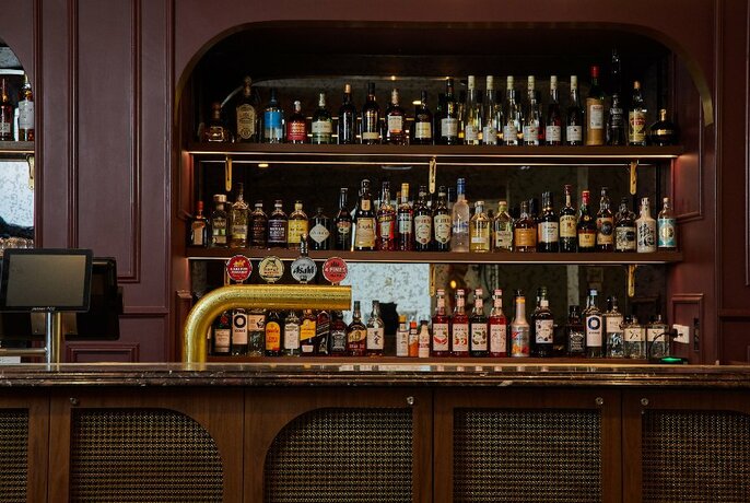 A bar with warm tones featuring shelves of bottles. 