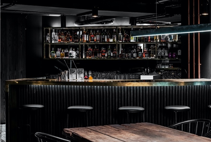 A dimly-lit black cocktail bar 