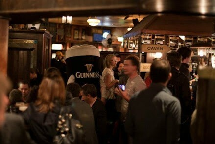Crowded pub with a large Guinness model.