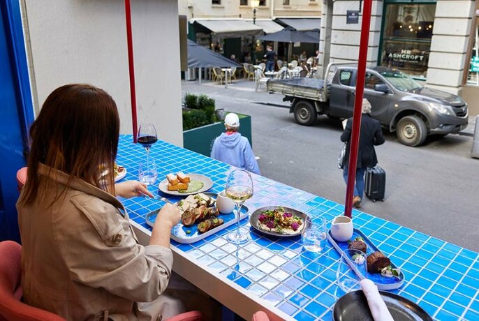 Person dining in an open air pop-up restaurant in a laneway.