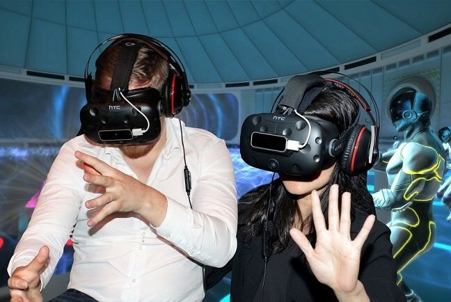 Two people wearing virtual reality goggles and headsets.