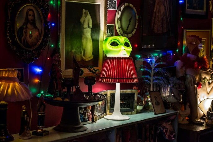 Interior dimly-lit corner of the Butterfly Club showing a collection of kitsch including lamps, object d'art and paintings.