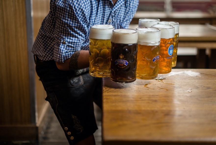 Person carrying six large mugs of German beer.