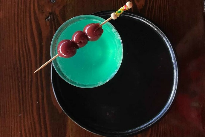 Cocktail viewed from above with garnish of cherries on a stick.