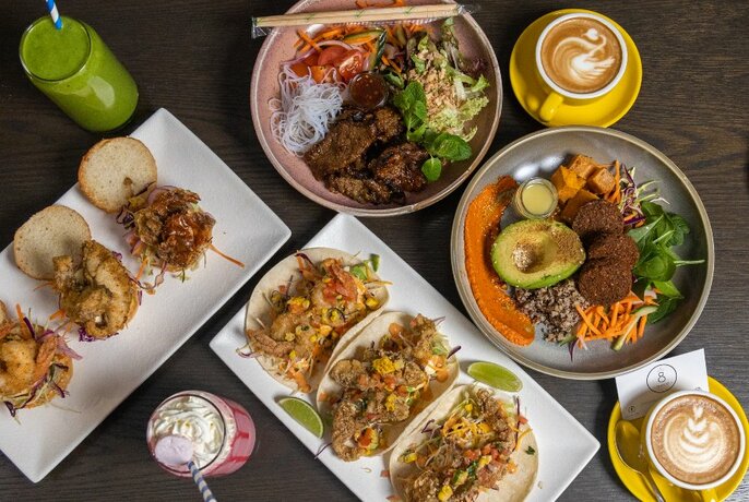 A variety of dishes, smoothies and coffees on a table
