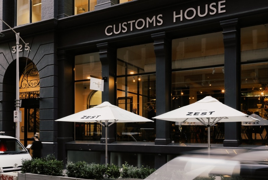 Customs House exterior with cafe umbrellas and tables.