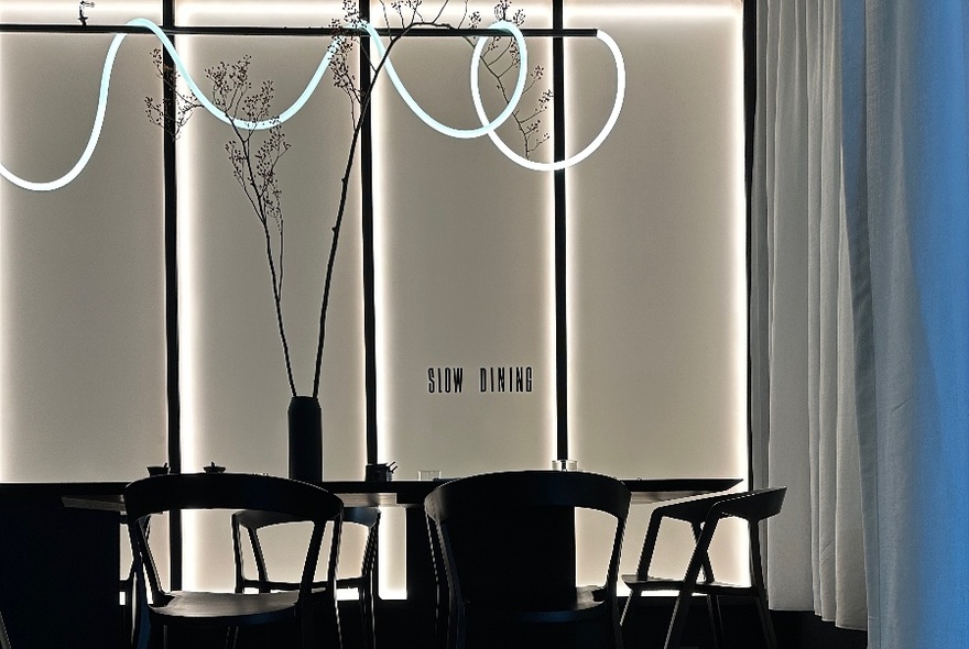 Black and white restaurant interior, with a black table and chairs and a modern light fitting hanging from the ceiling.