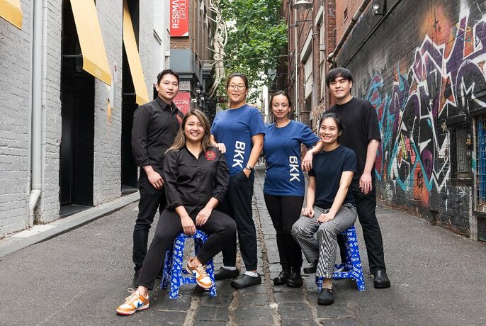 A group of chefs posing in a street-art covered laneway.