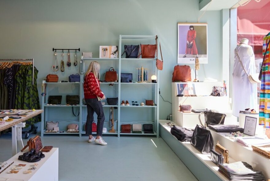 A woman browsing bags and accessories at an Elk shop. 