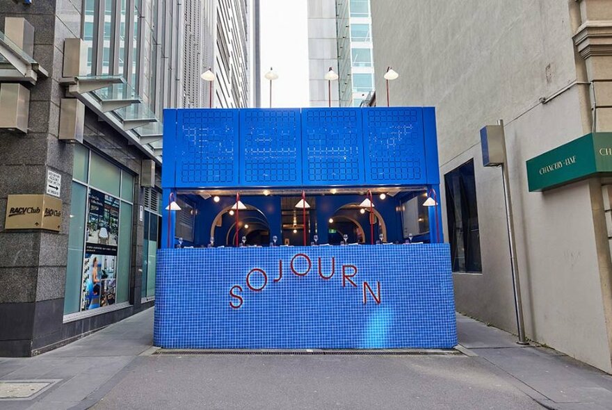 Bright blue pop-up Sojourn bar and restaurant in a laneway.