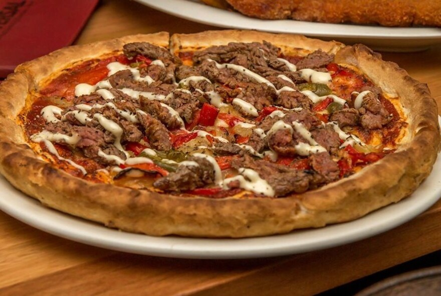 Meat pizza drizzled with white sauce.