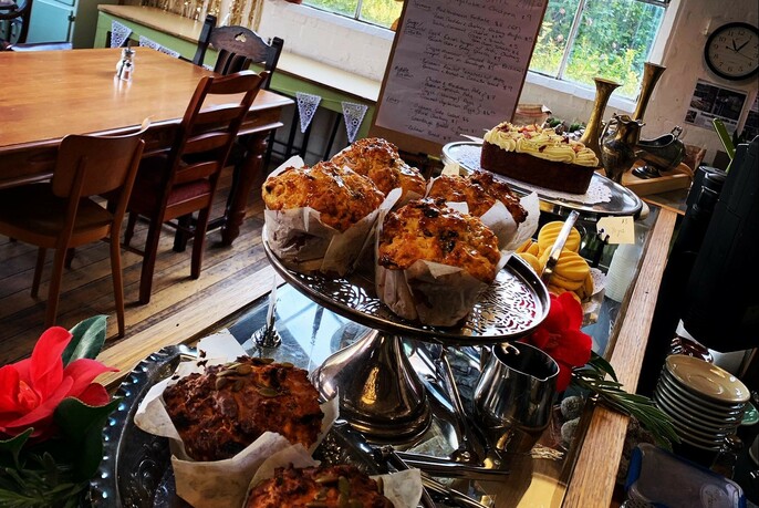 Muffins and cake on display on a cafe counter.