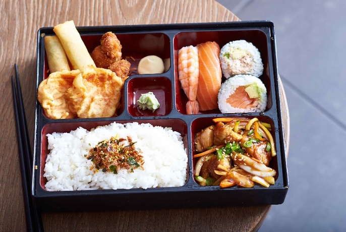 A bento box filled with rice, ngiri, sushi, fried food and more. 