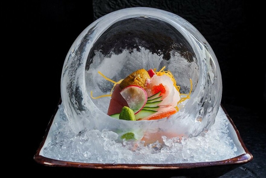 Round glass dish filled with seafood salad set on a bed of ice.