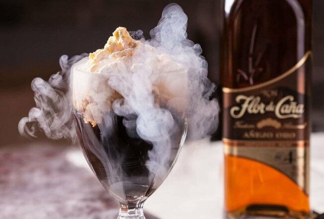A cocktail with whipped cream and nitro smoke on top.