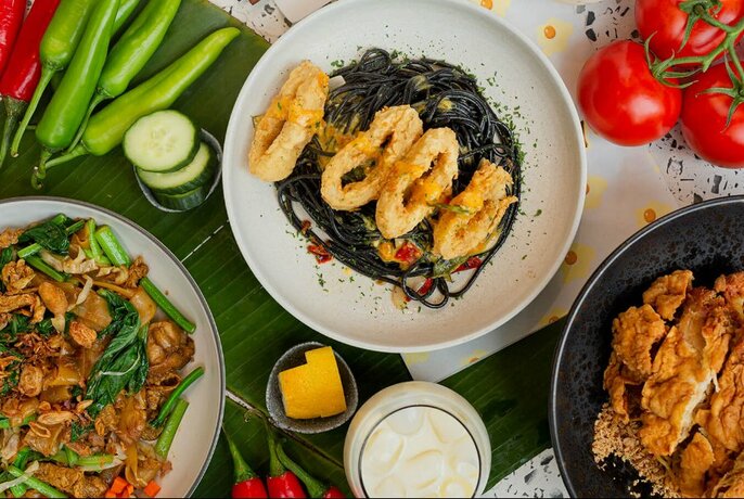 Squid ink noodles and calamari surrounded by other Indonesian dishes.