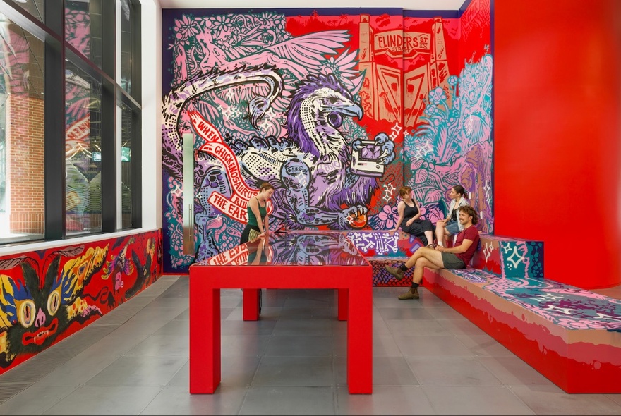 Exhibition space with red table and walls with graffiti-style artwork.