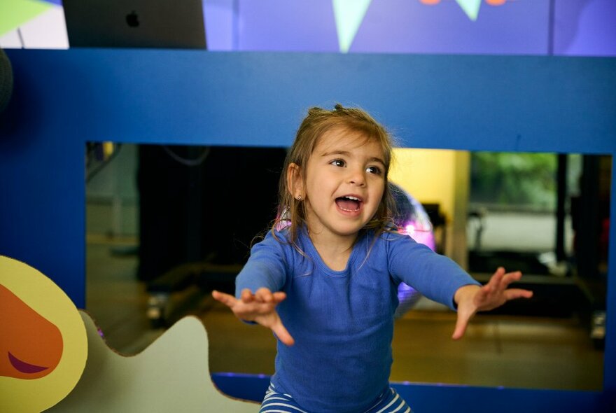 A young child dancing with arms oustretched and smiling.