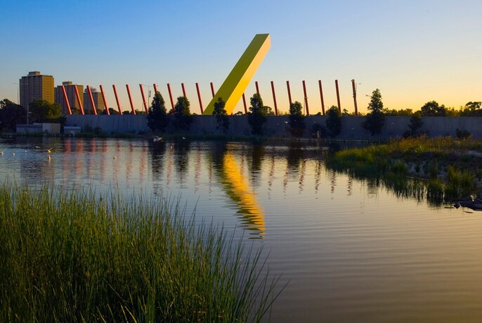 Lake and reeds of Trin Warren Tam-boore  urban wetland in Royal Park with giant yellow sculptural work on CityLink reflected in the water.