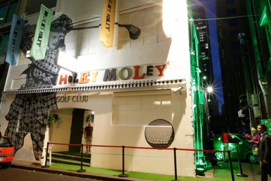 Exterior of Holey Moley mini golf venue at night.