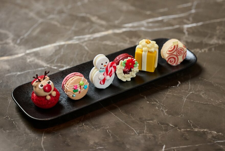 A rectangular plate of six delicate and Christmas themed sweet treats and petits fours.