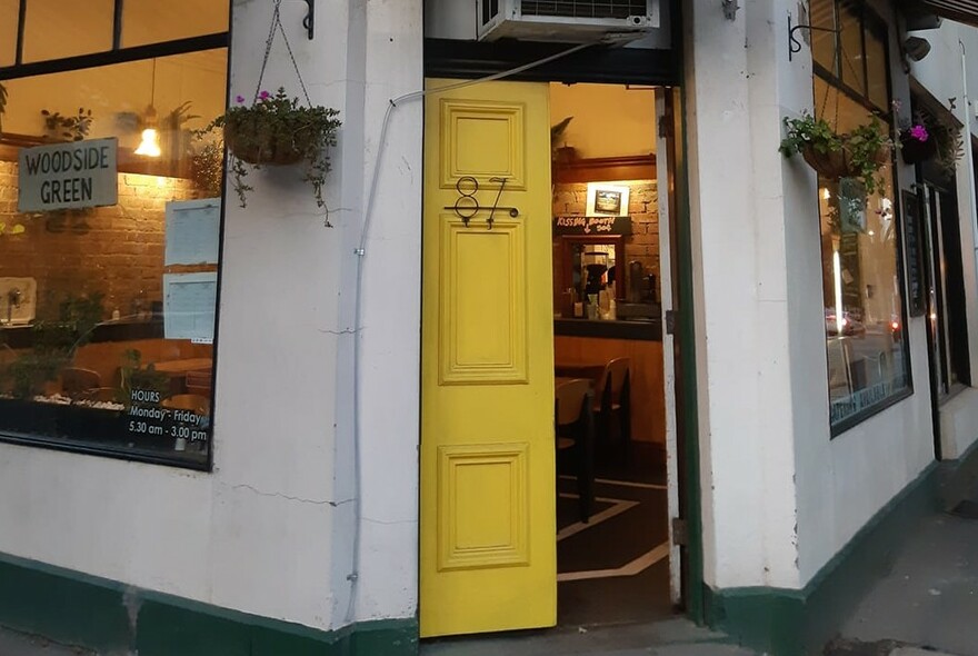 Corner shopfront, white with a yellow door.