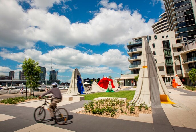 Cyclist passing a sculpture park on NewQuay Promenade.