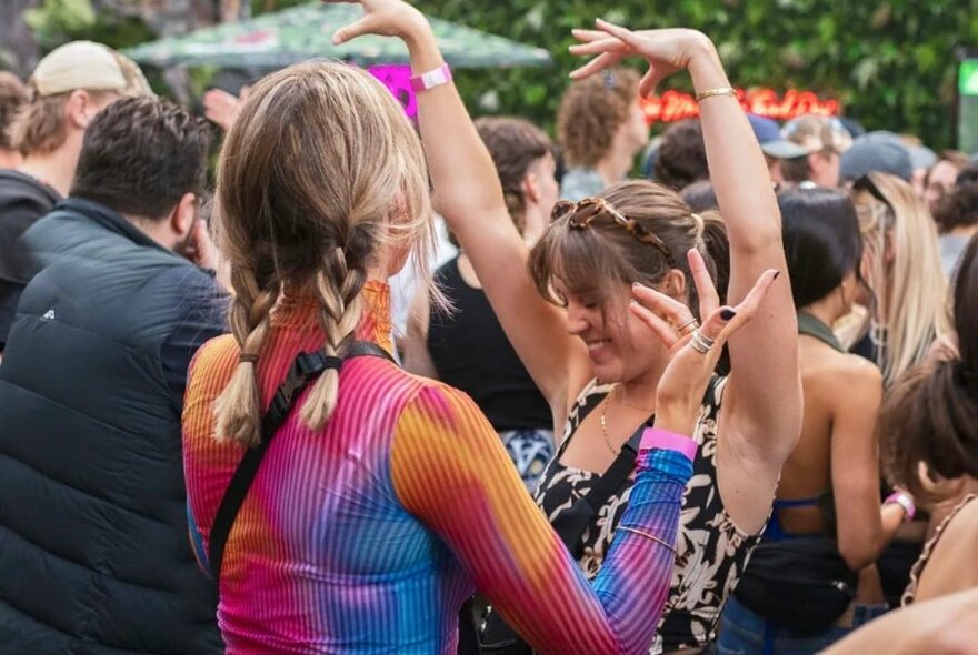 Dancers in a crowd, waving their arms to music.