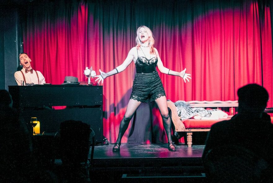 A woman performs in a cabaret setting with a pianist accompanying her. 