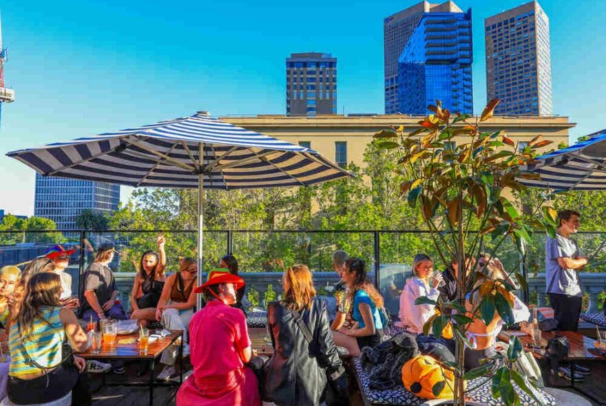 People sitting beneath umbrellas at a rooftop bar