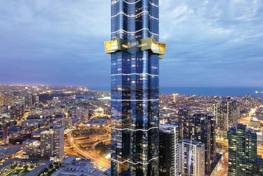 A very modern tall building in a city with a gold  floor sticking out from the rest of the structure.