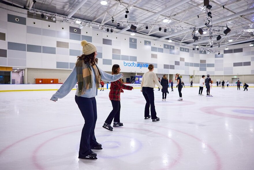 Crowds of people ice skating on an indoor rink.