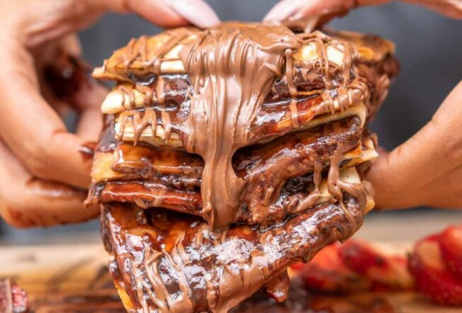 woman holding pastry covered in Nutella and strawberry