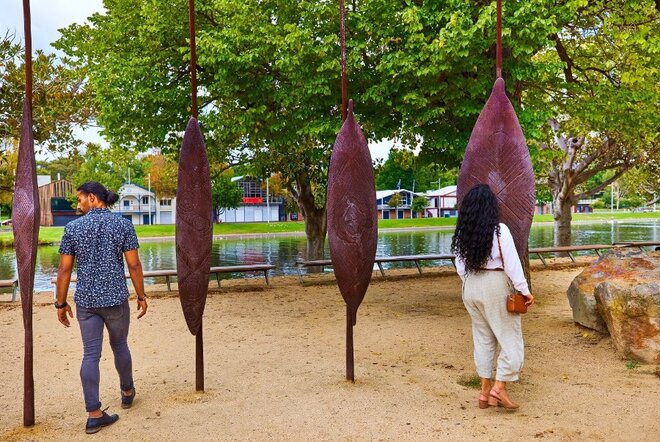 A man and woman observing the Birrarung Wilam sculptures. 