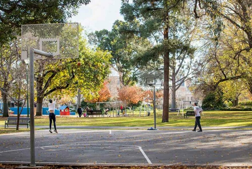 Two friends playing basketball in public gardens.