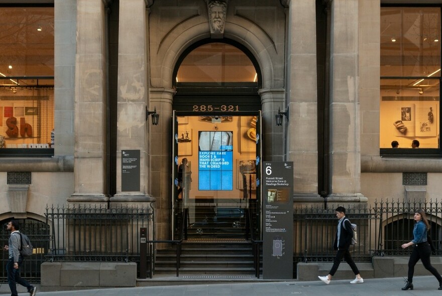 People walk past an entrance to State Library Victoria building.