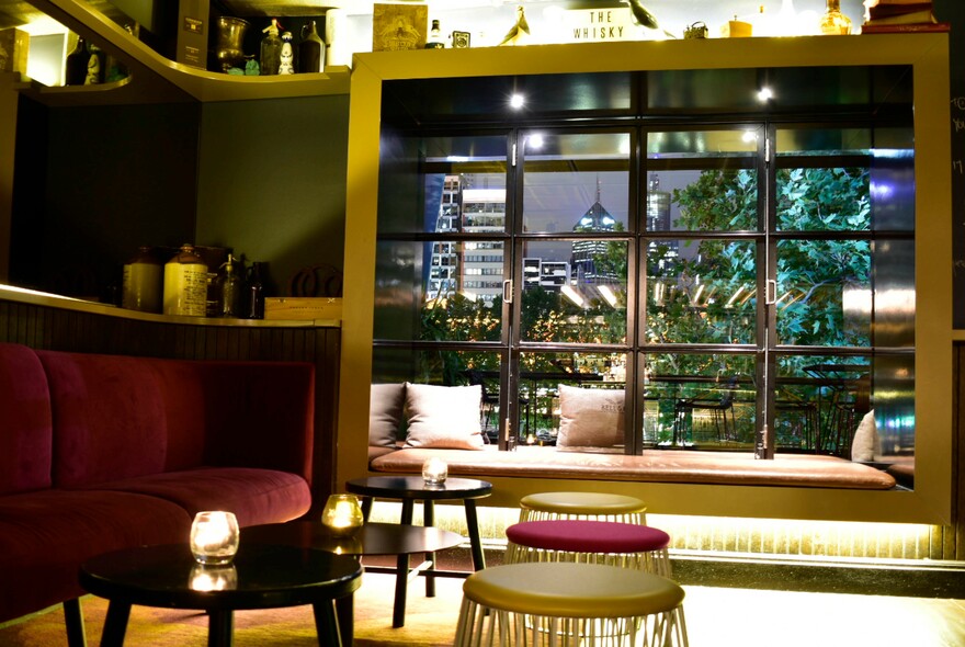 Cosy bar setting and window looking out to the cityscape at night.