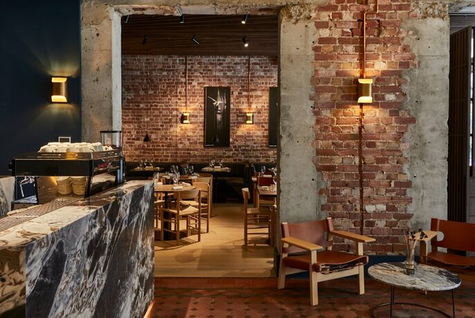 Restaurant interior with bare brick walls and wooden furniture.