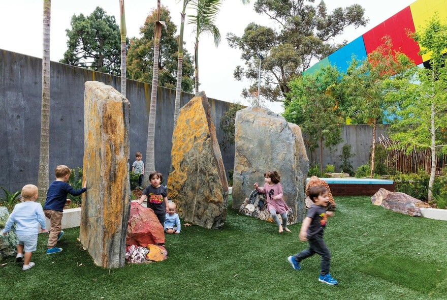 Young children playing around some large standing stones.