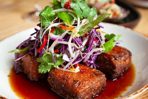 A sticky pork dish with herbs on top.