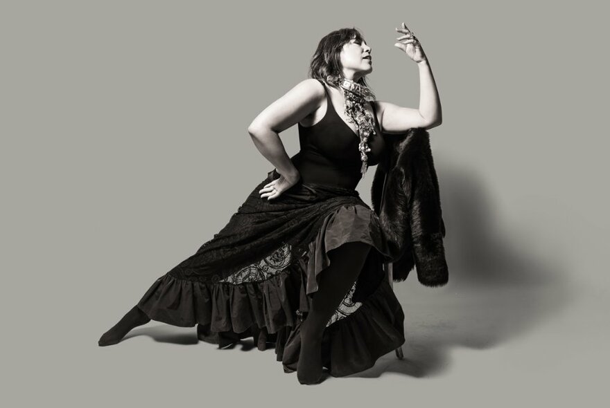 Singer Kate Ceberano in a pose with her leg stretched out and arm raised, wearing a flowing dark dress.