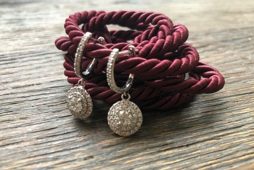 Pair of diamond earrings on coiled red cord.