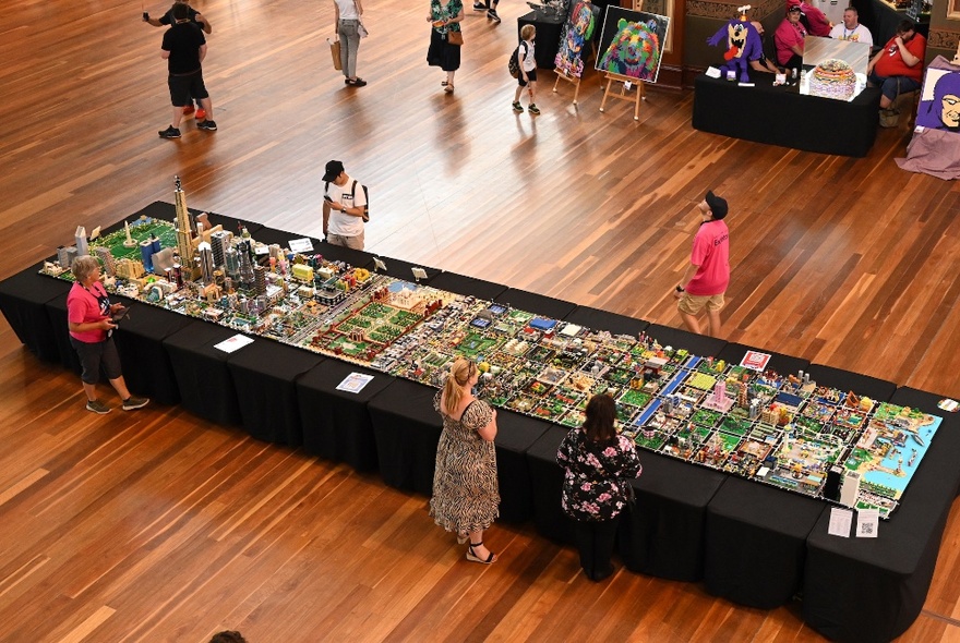 People standing around a long display table with Lego exhibits.