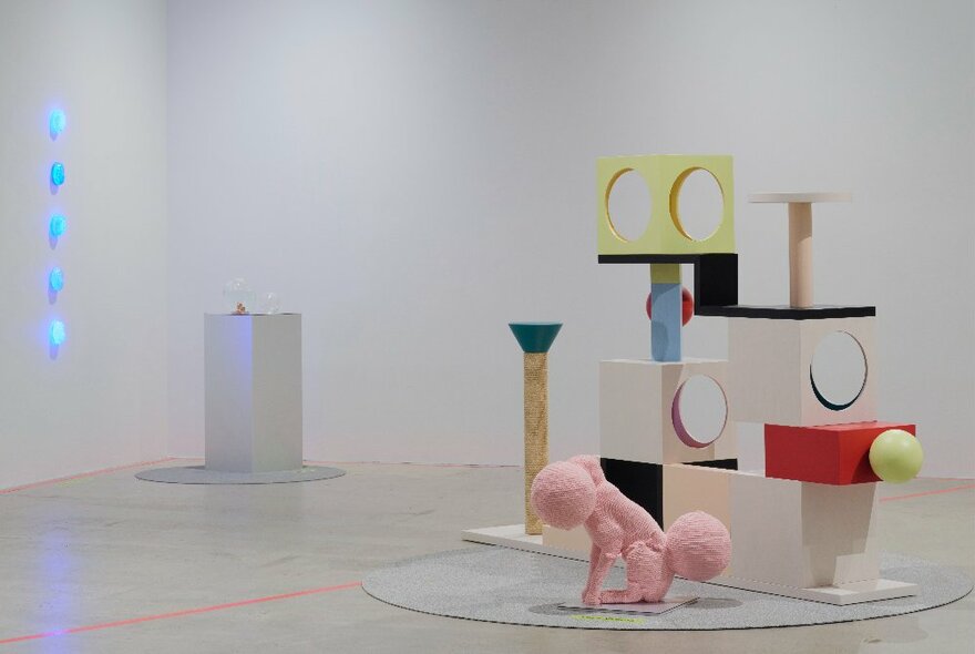 A large coloured sculpture comprising small steps, cubes and scratch posts, all joined together, for a cat to play on, on display in a white gallery environment.