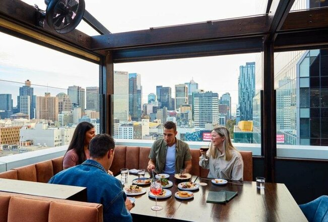 A group of four people dining at a table on a rooftop bar