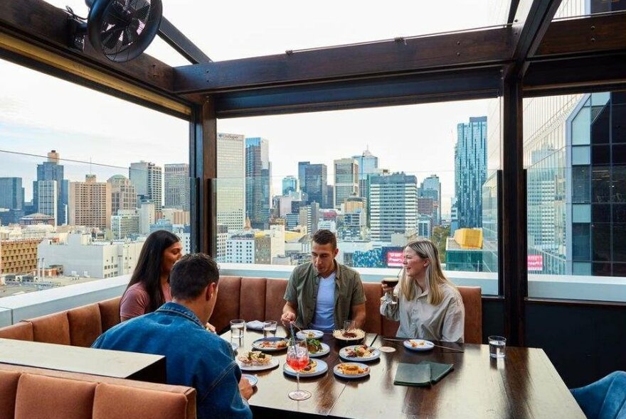 A group of four people dining at a table on a rooftop bar