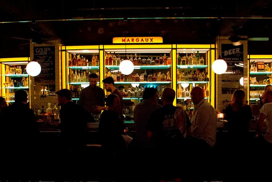 A dark bar crowded with people at Bar Margaux. 