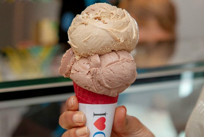 Hand holding double scoop ice-cream cone.